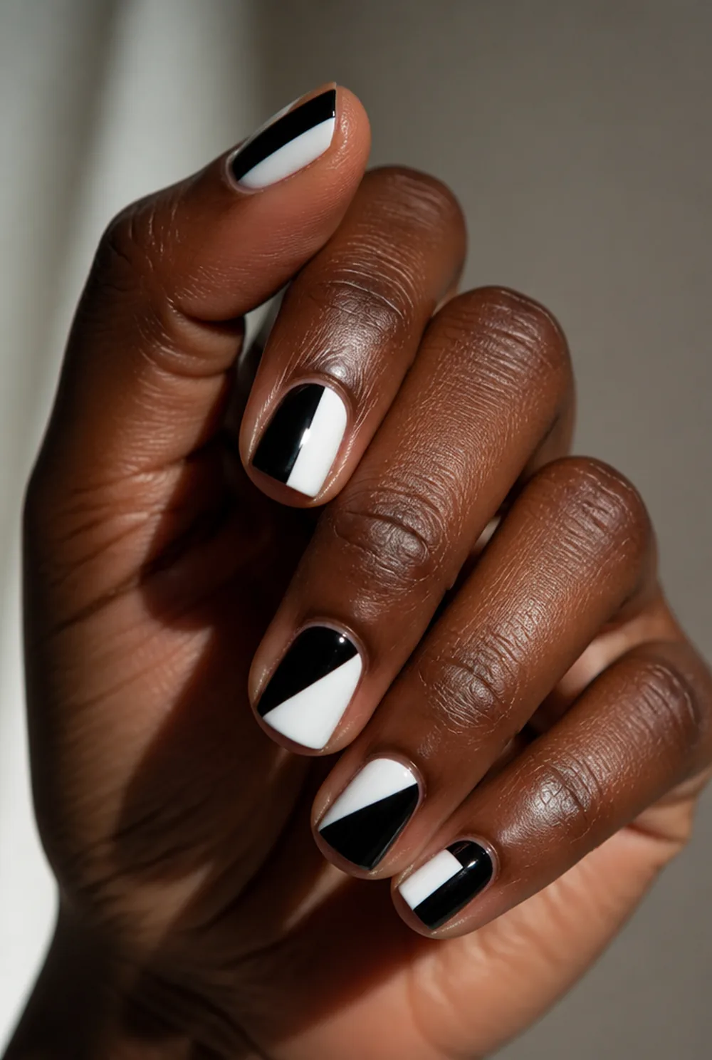 black and white split nail art on deep brown skin
