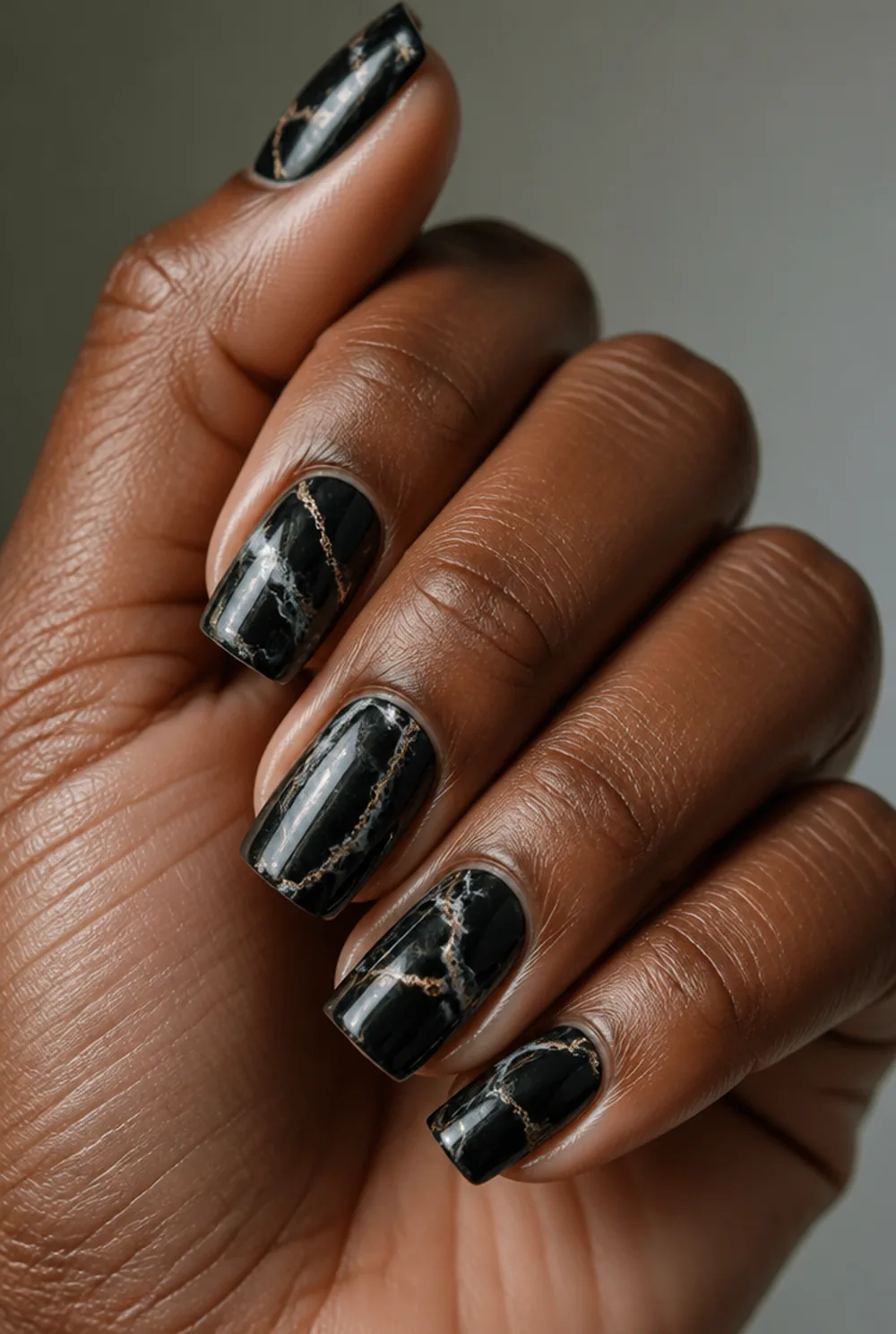 black marble nail art on deep brown skin