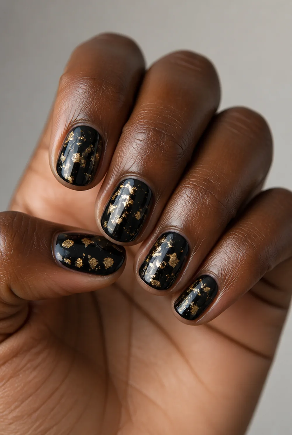 gold-fleck black nail art on deep brown skin