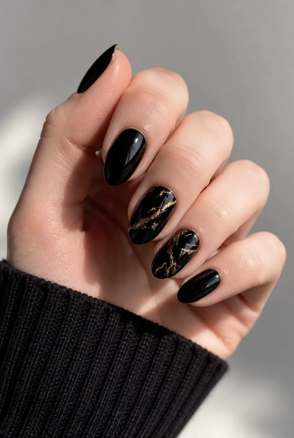 gold-vein black marble nail art on fair skin, short length