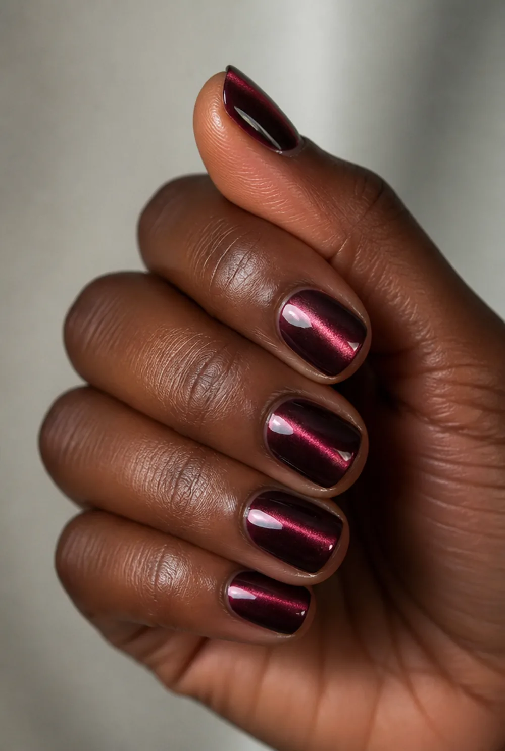 burgundy cat eye nail art on deep brown skin