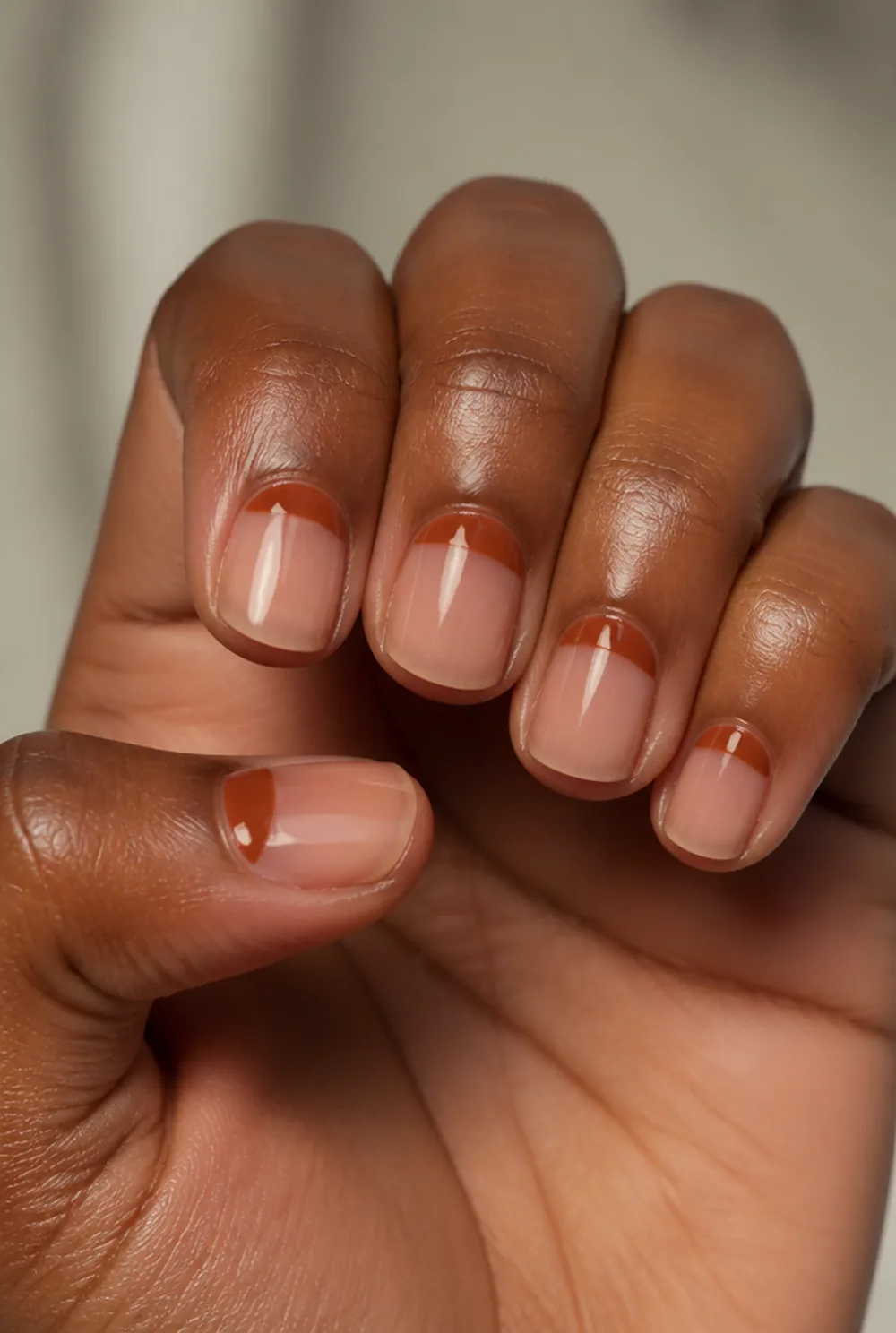 rust half-moons nail art on deep brown skin