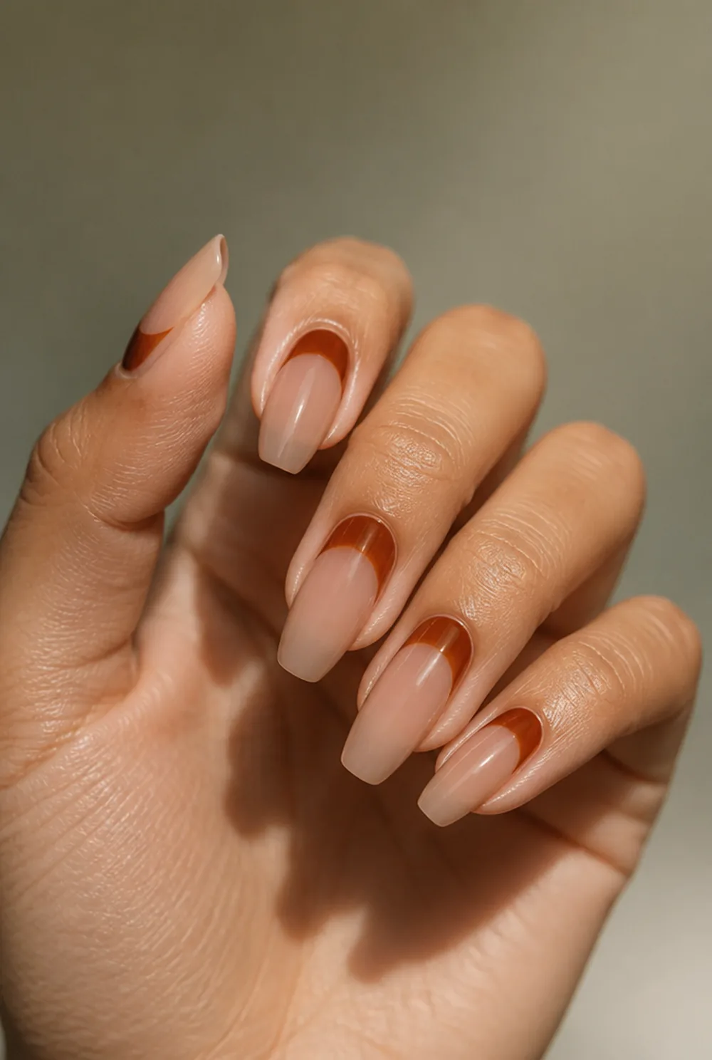 rust half-moons nail art on olive skin, long length