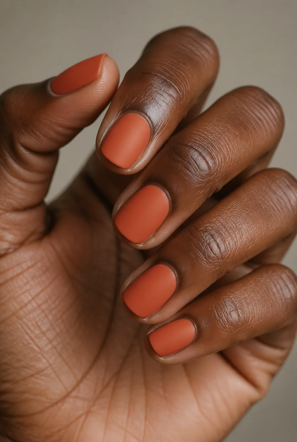 matte pumpkin nail art on deep brown skin