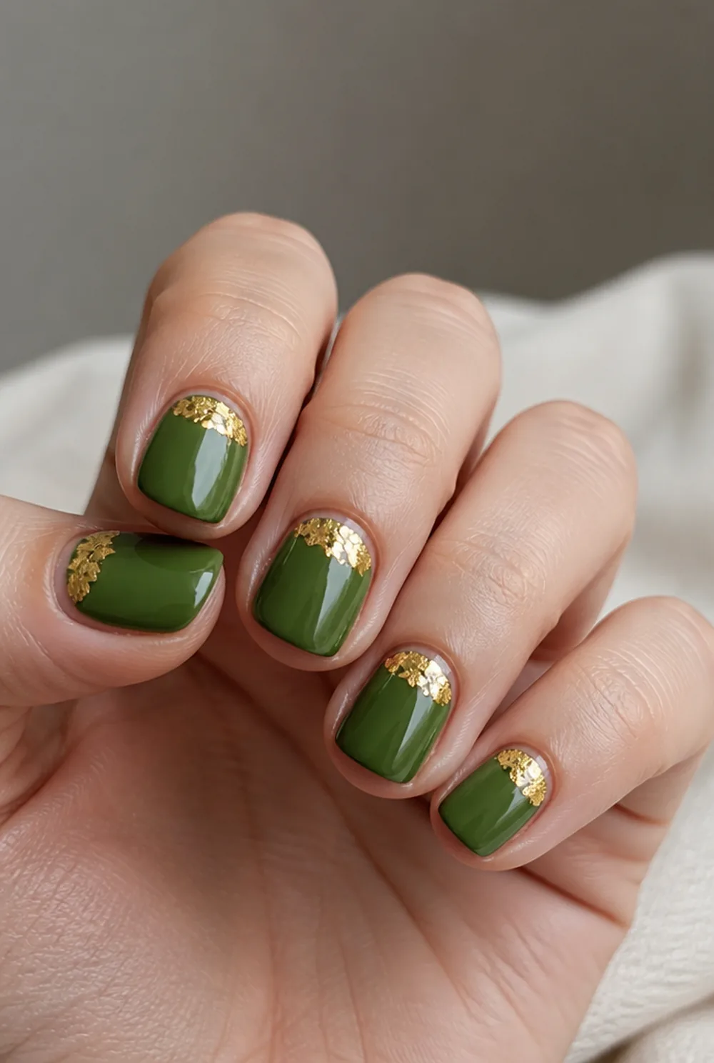 olive and gold leaf nail art on fair skin, short length