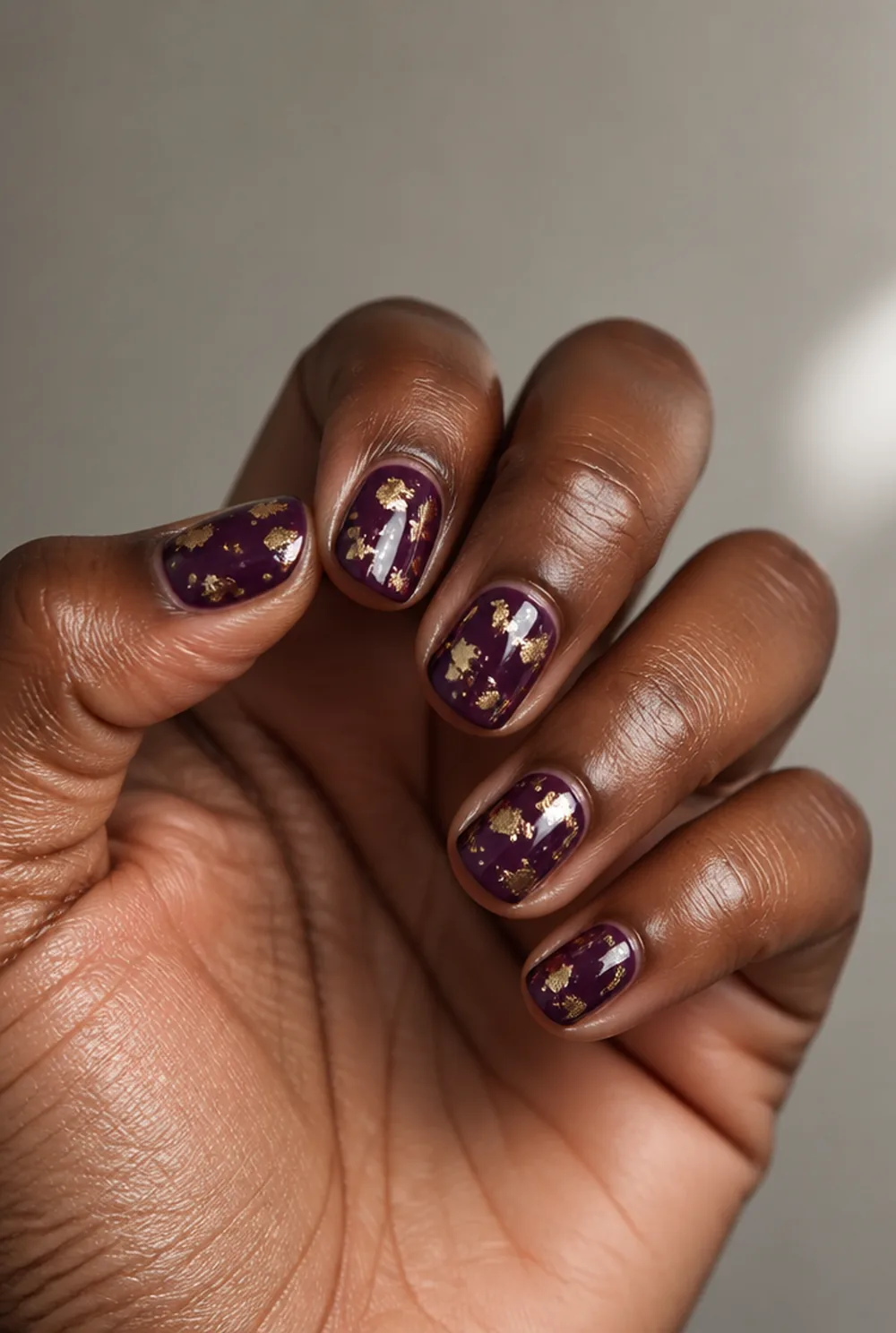 plum with gold foil nail art on deep brown skin - PolishedAndPrettyNails.com plum with gold foil nail art on deep brown skin