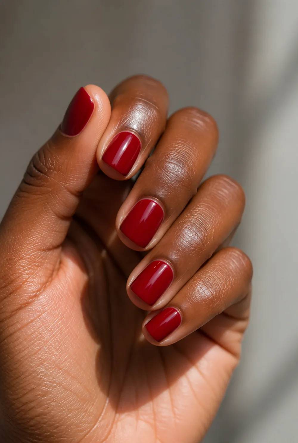 solid cherry gel nail art on deep brown skin