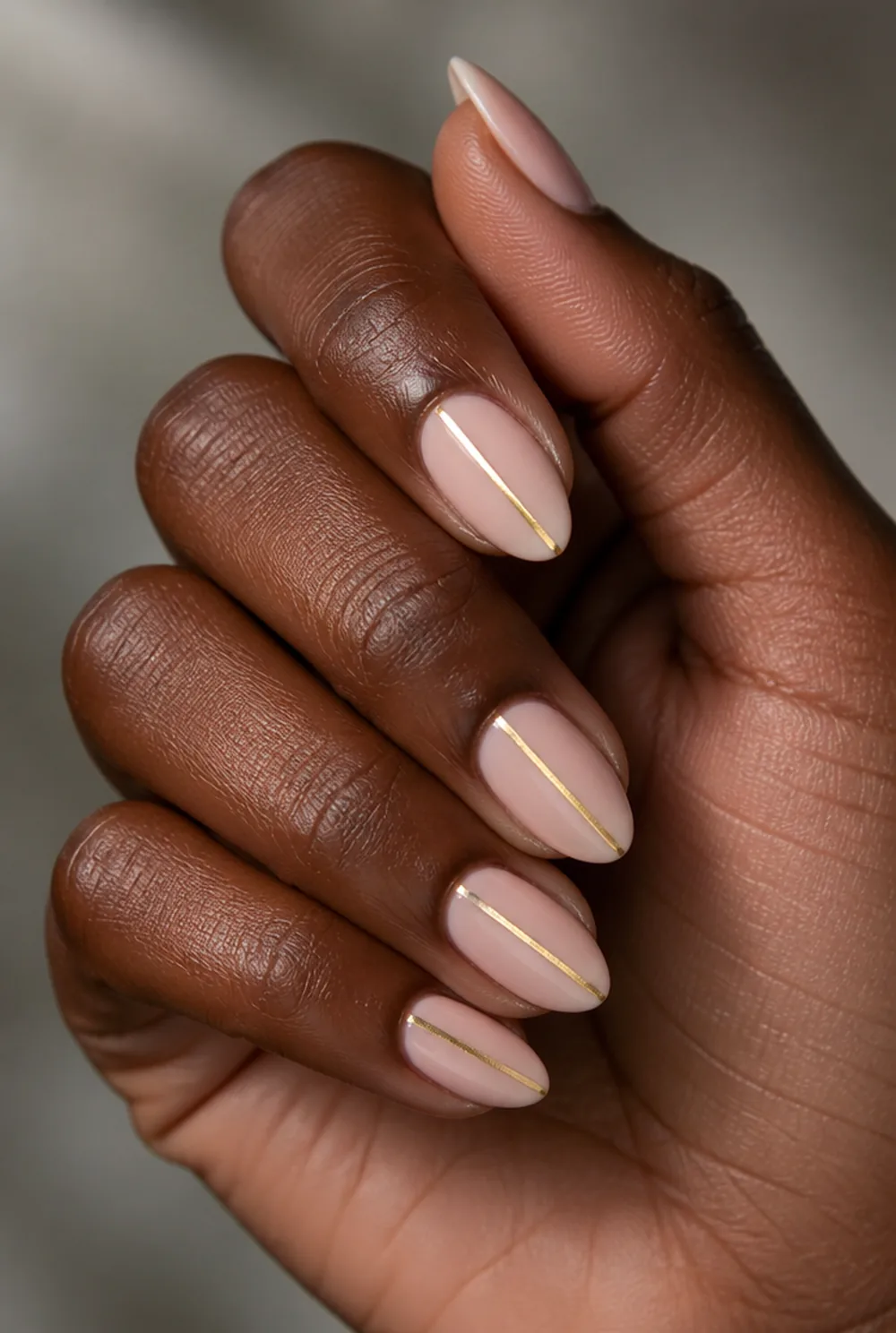 almond with gold line nail art on deep brown skin