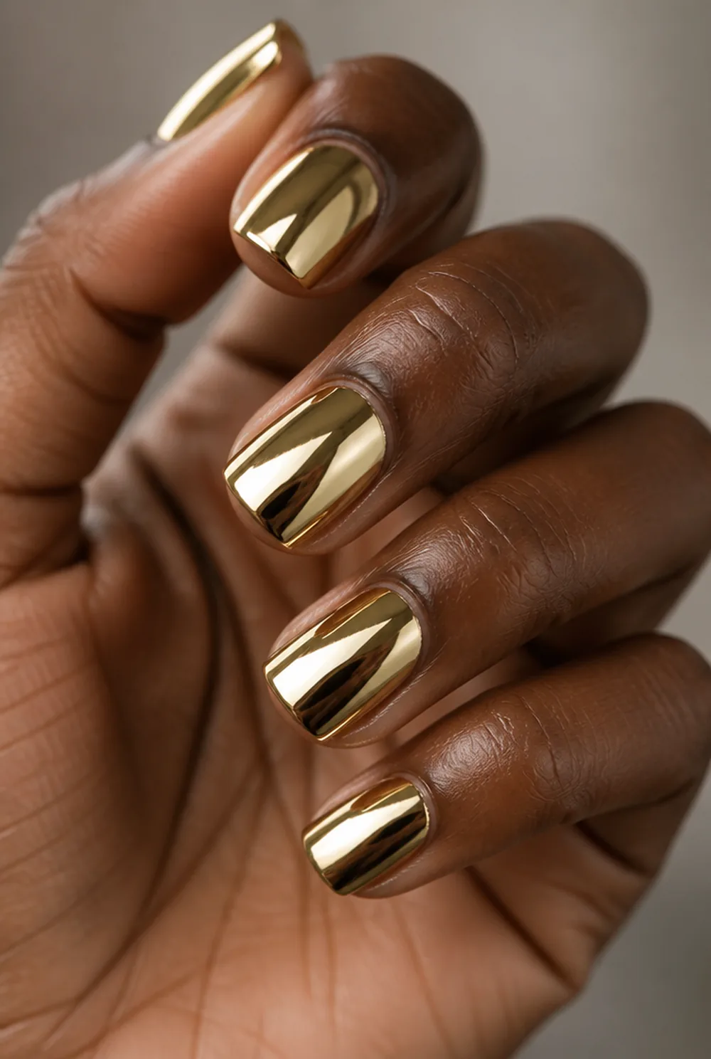 gold mirror chrome nail art on deep brown skin