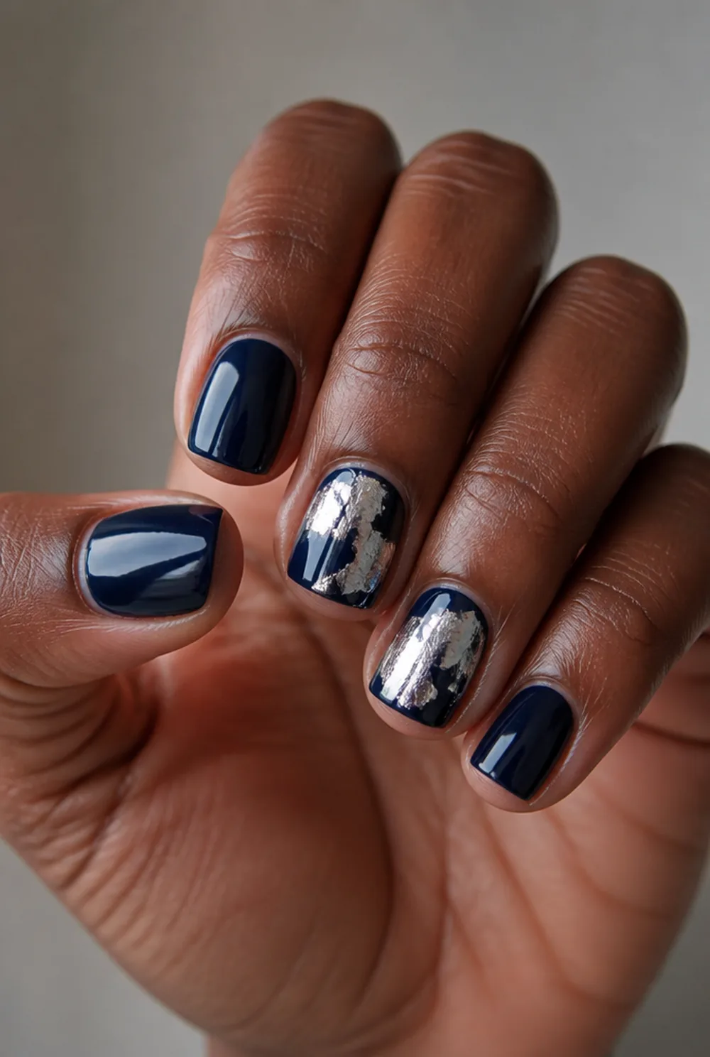 blue and silver foil nail art on deep brown skin