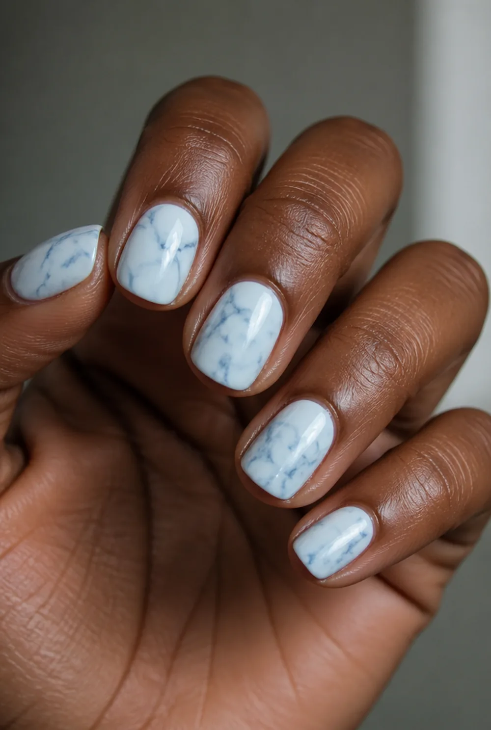 blue and white marble nail art on deep brown skin