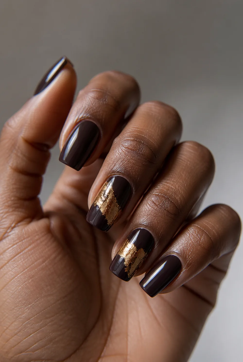 coffin with gold foil nail art on deep brown skin