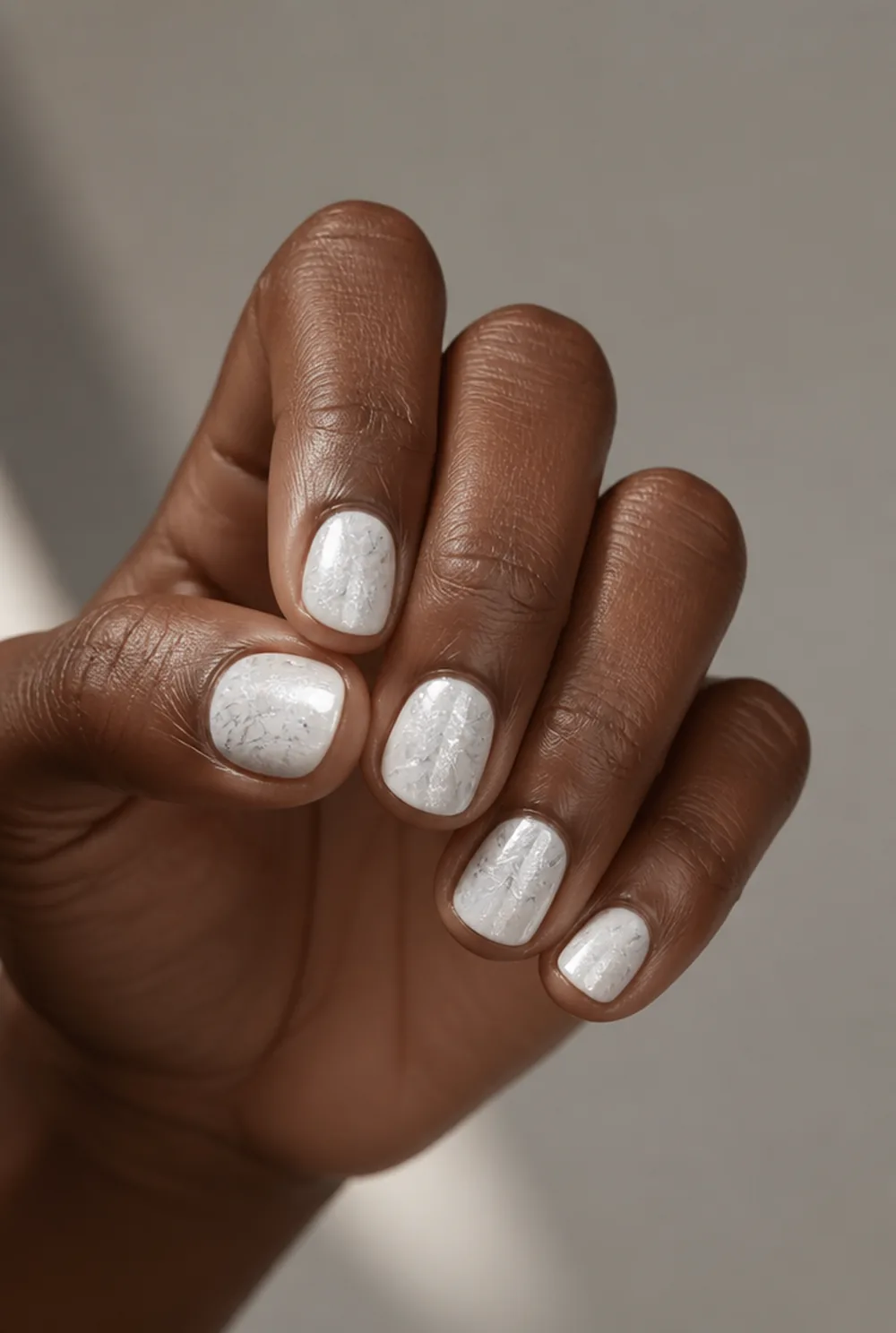 white and silver frost nail art on deep brown skin
