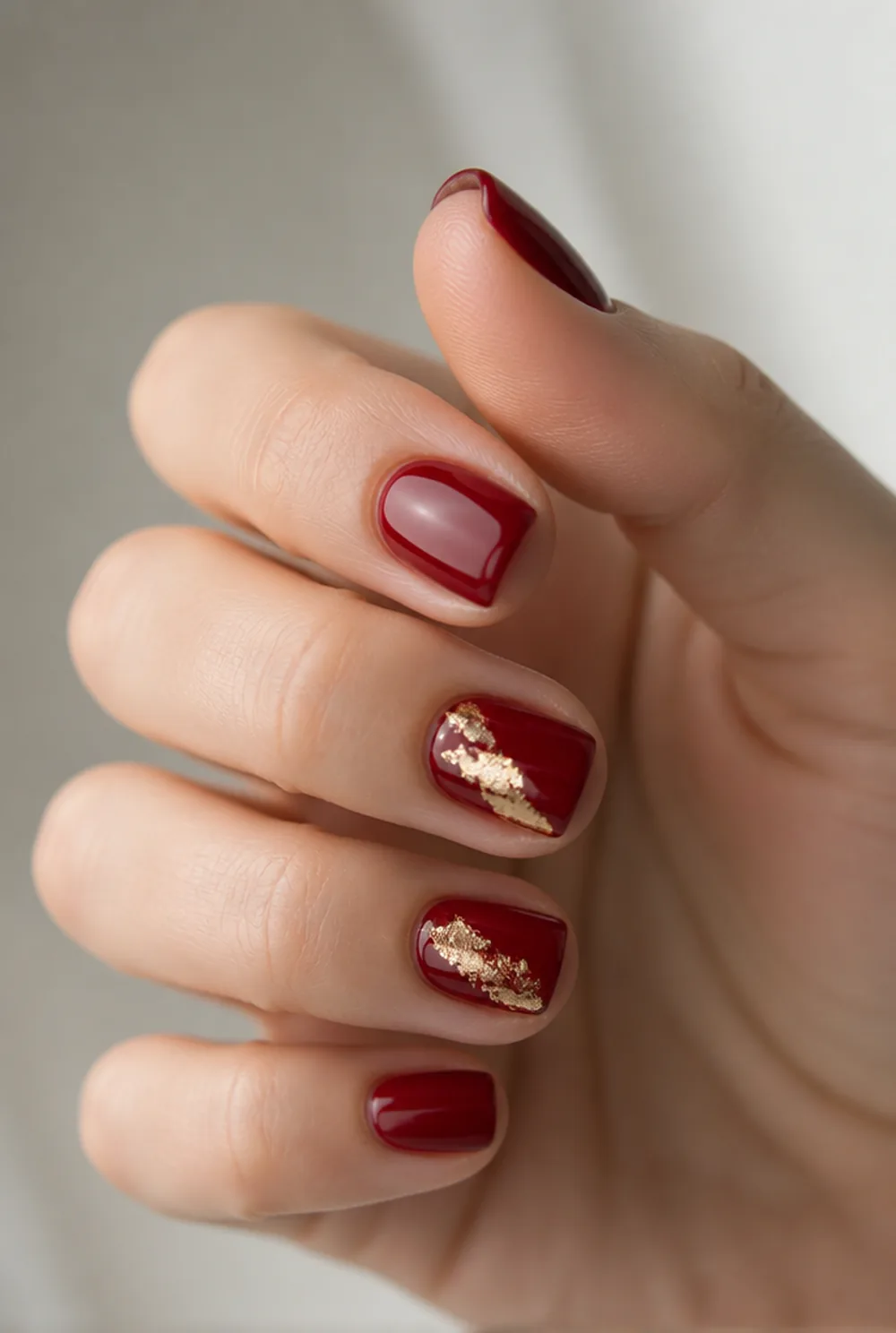 red and gold foil nail art on fair skin, short length
