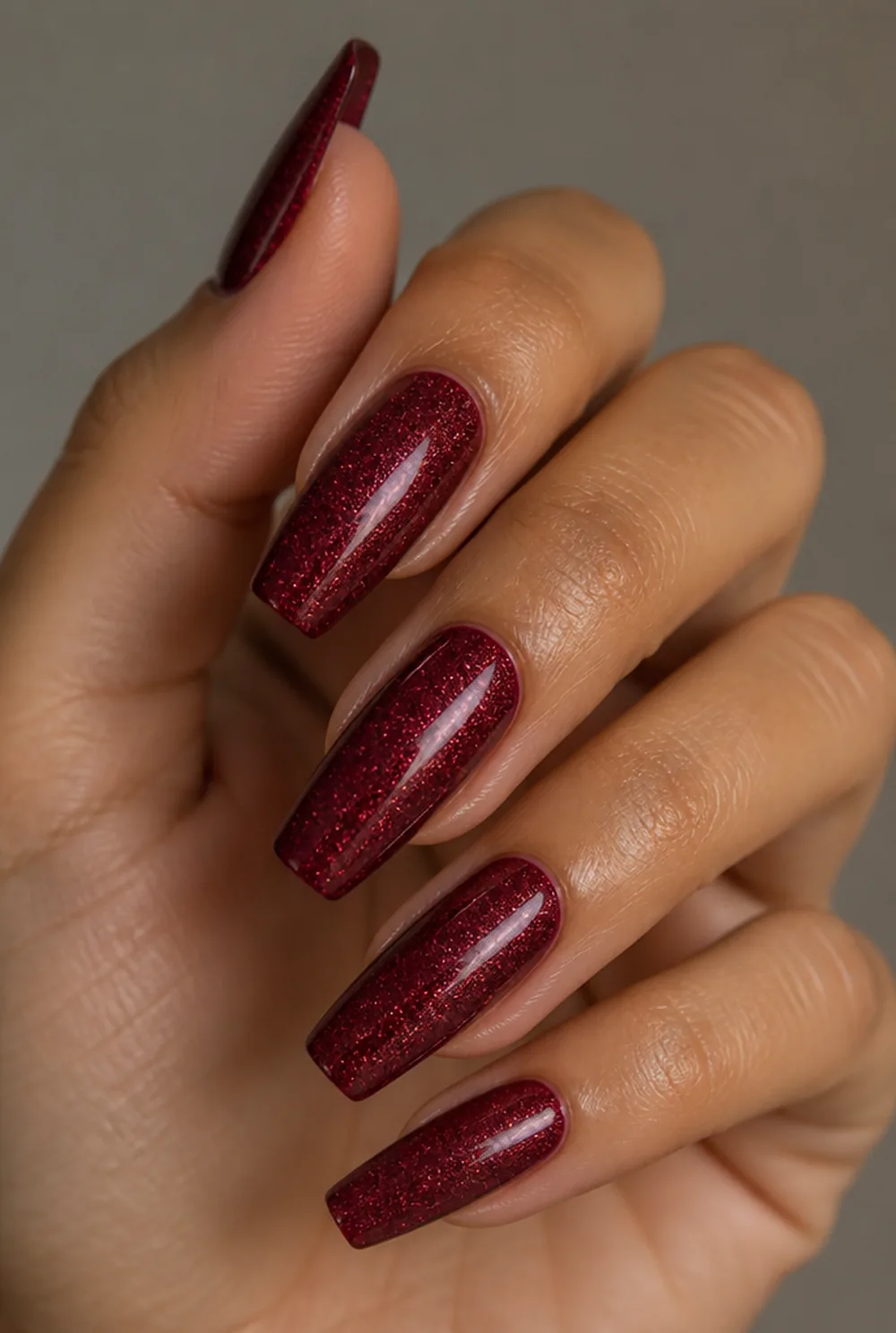 glitter over deep red nail art on olive skin, long length