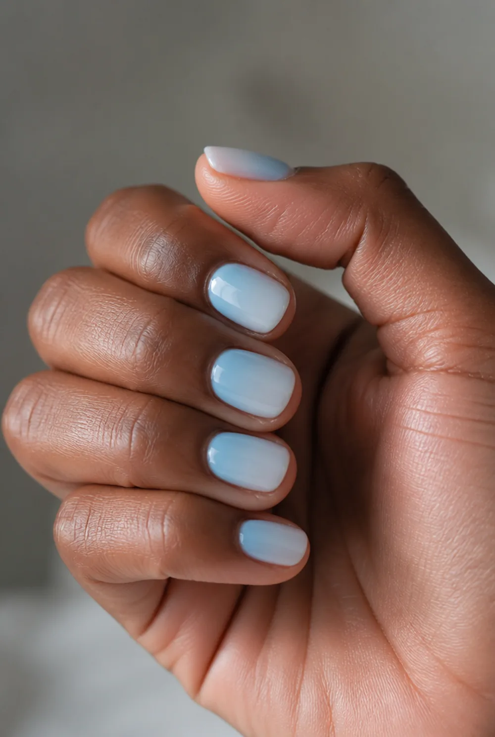 milky blue nail art on deep brown skin