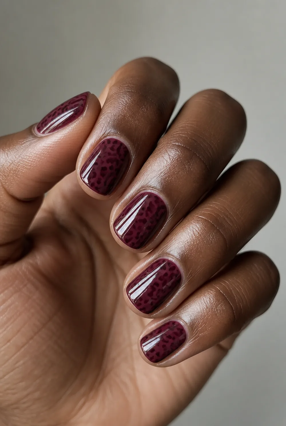 leopard on burgundy nail art on deep brown skin