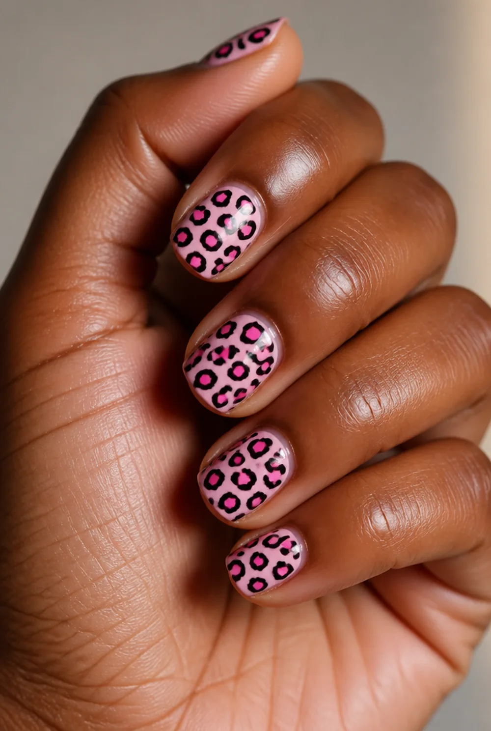pink leopard nail art on deep brown skin