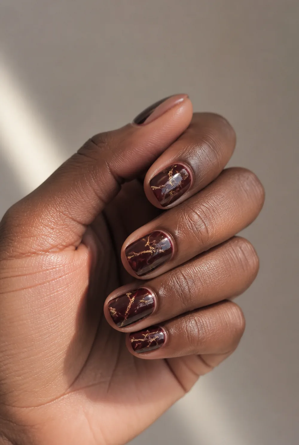 burgundy marble nail art on deep brown skin