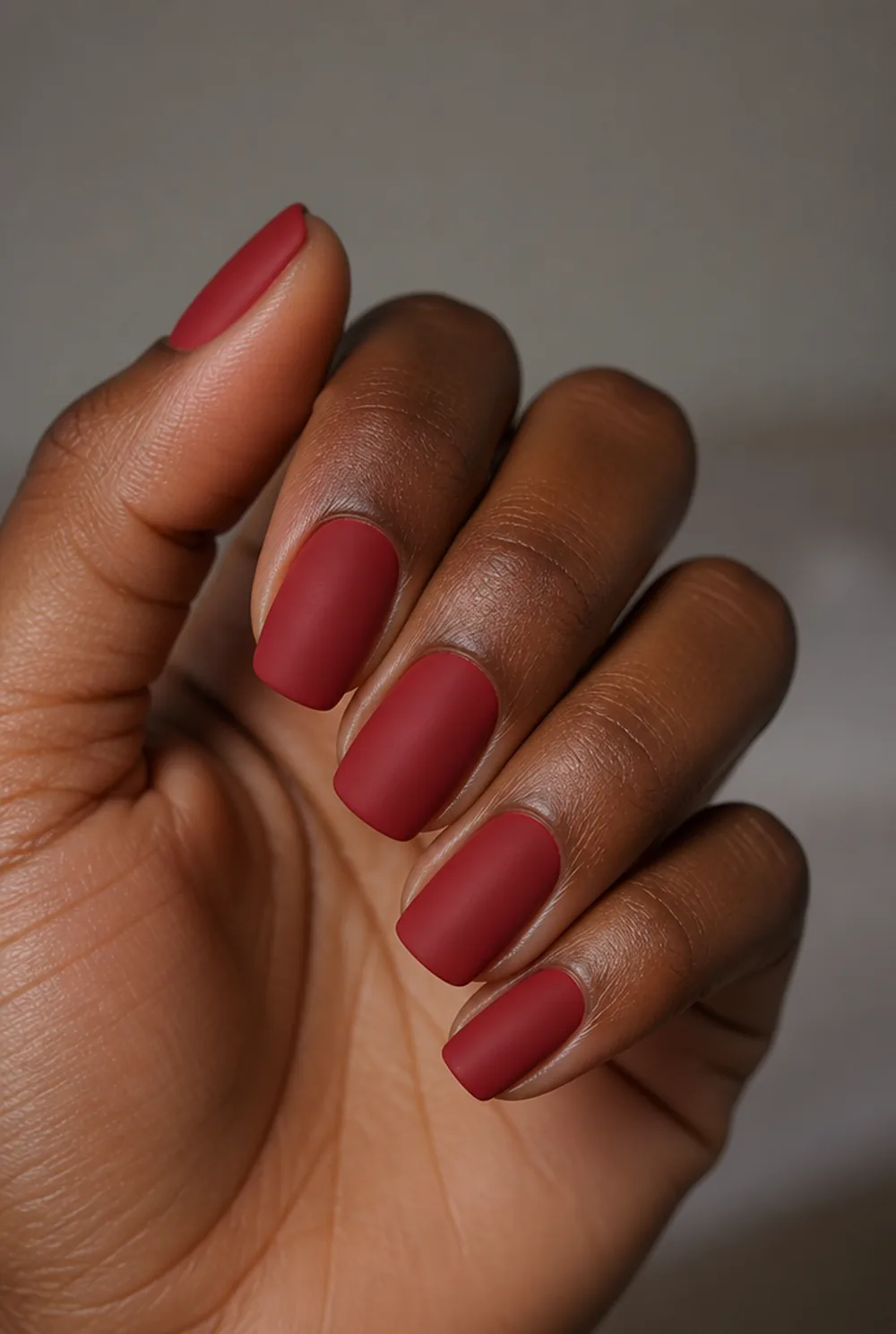 matte red nail art on deep brown skin
