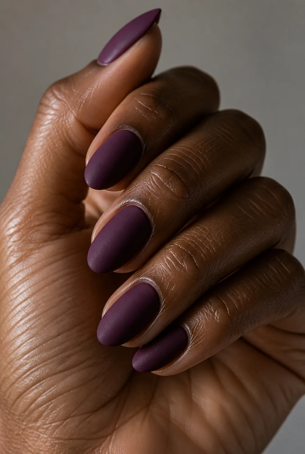 matte plum nail art on deep brown skin