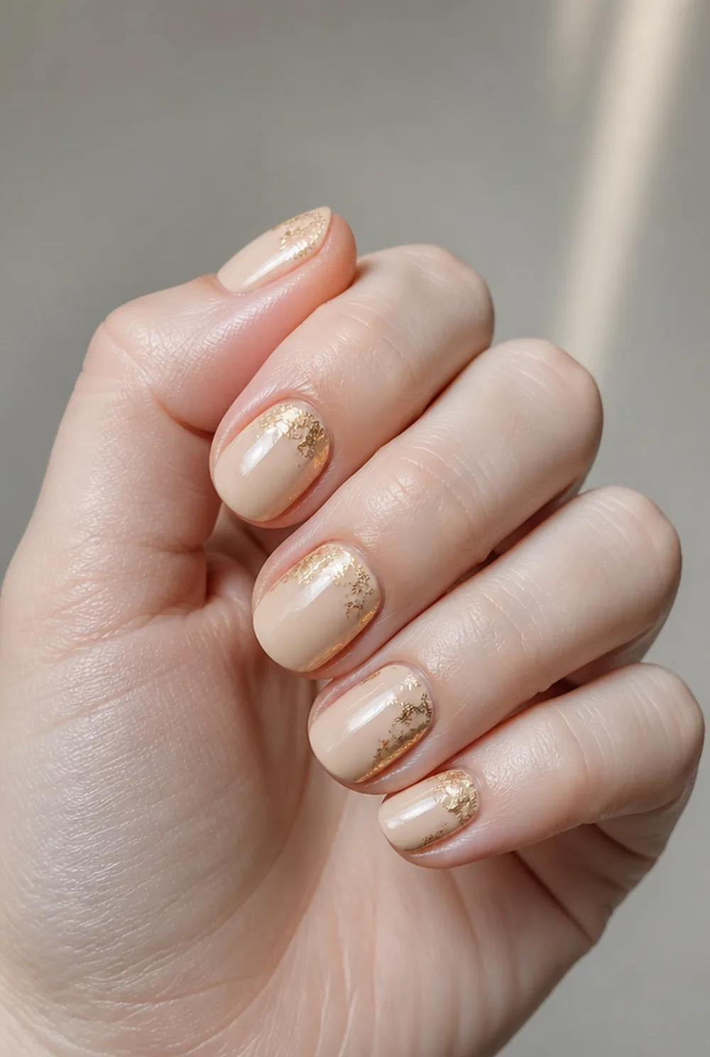 nude with gold foil nail art on fair skin, short length