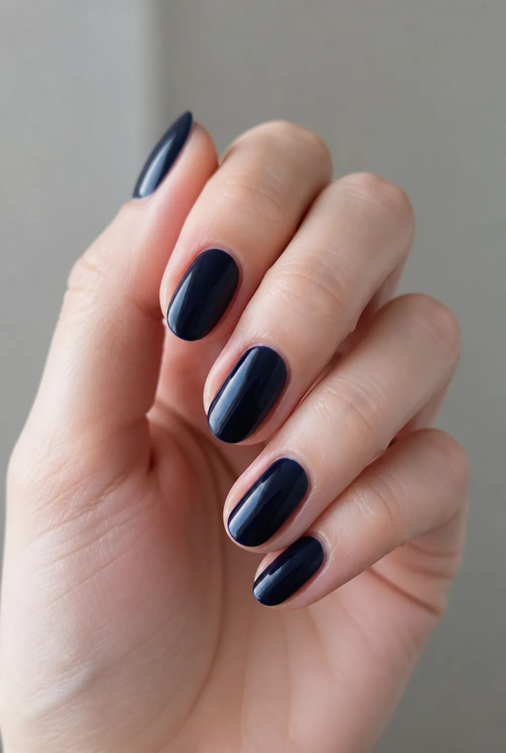 oval navy nail art on fair skin, short length