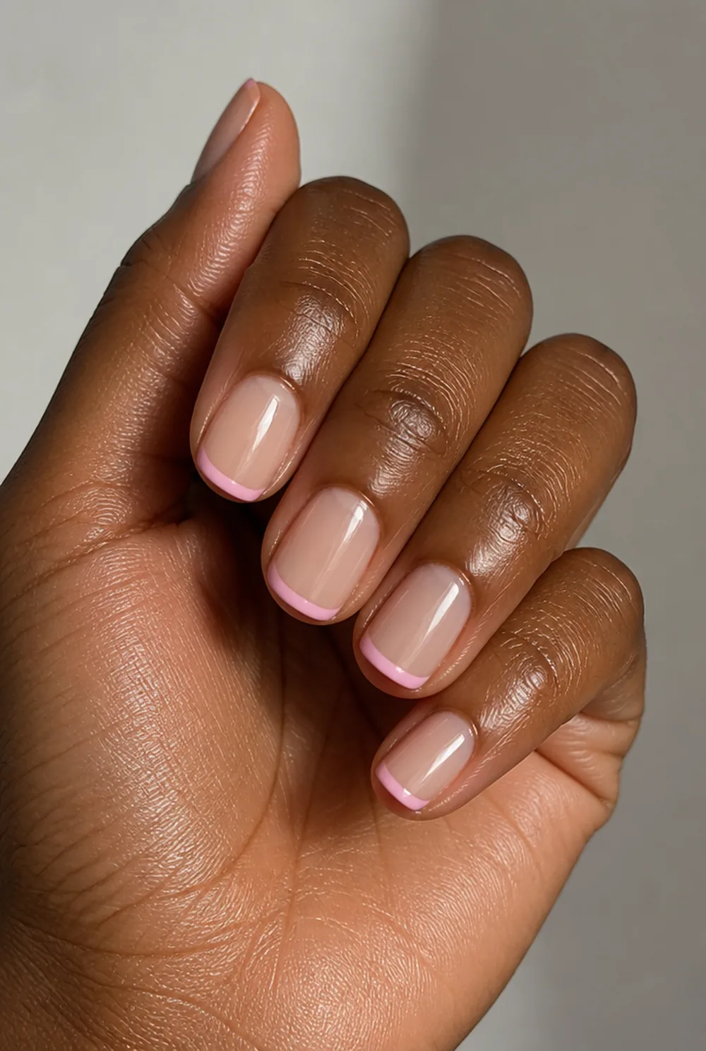 pink french tip nail art on deep brown skin