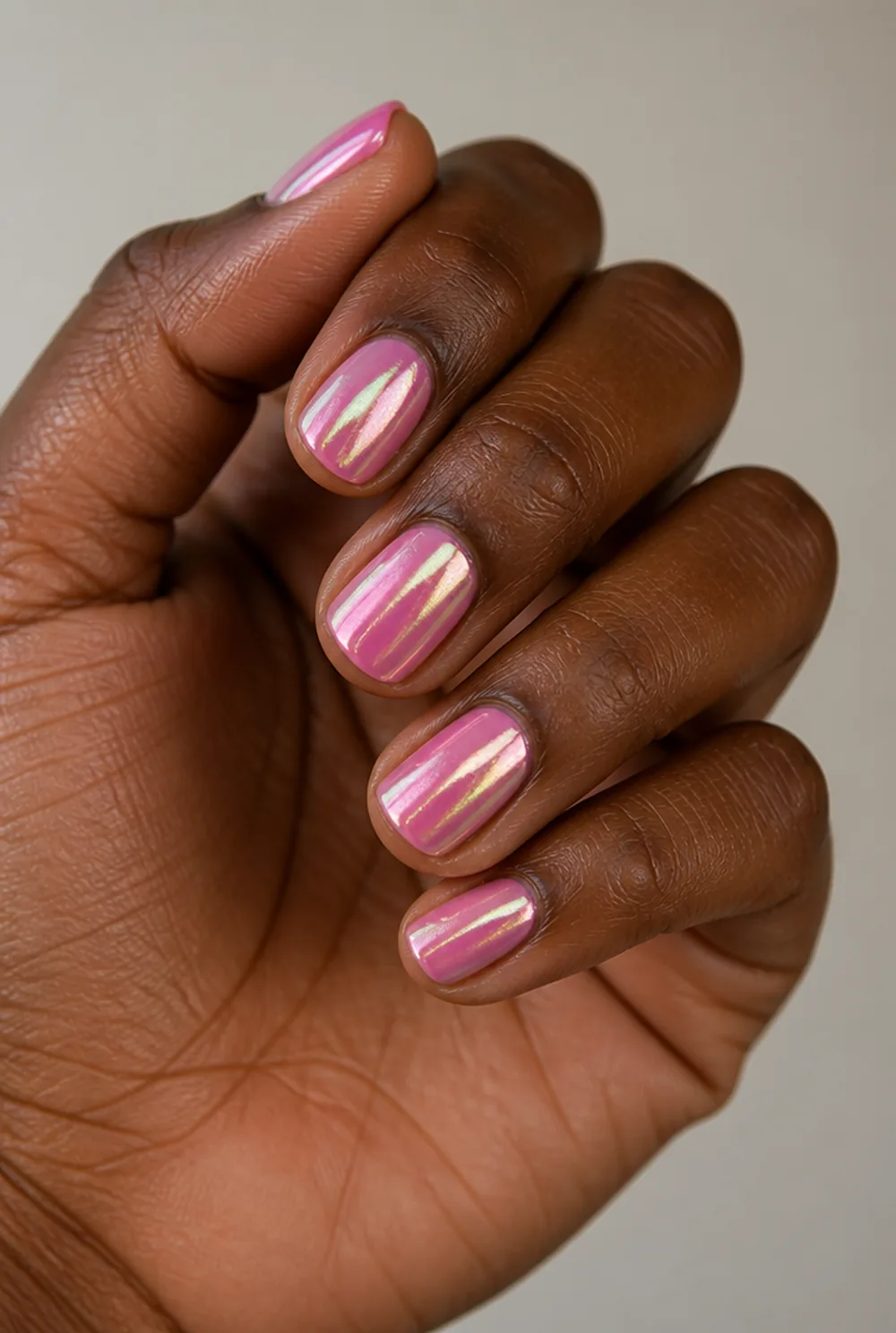 pink chrome nail art on deep brown skin