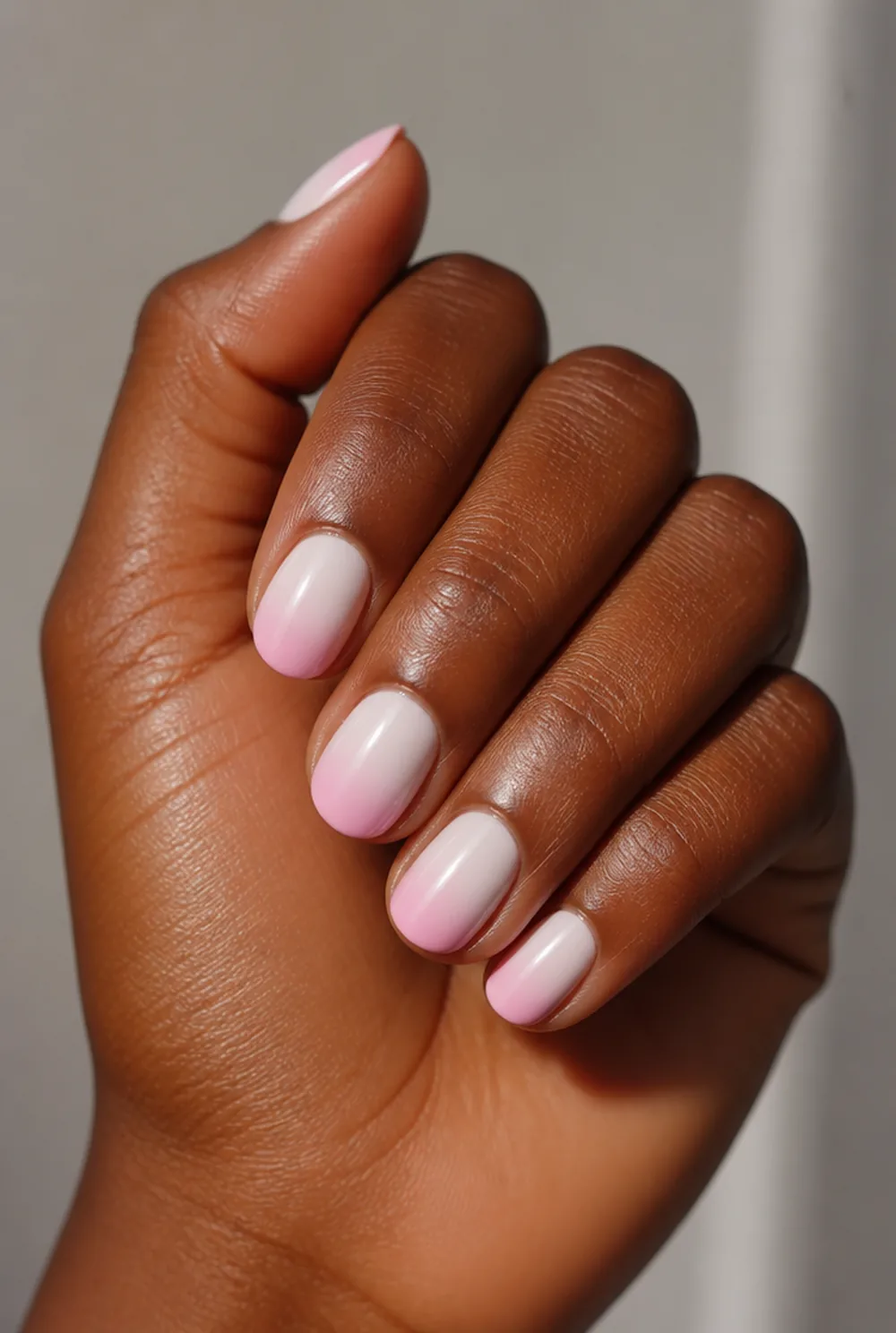 pink and white ombre nail art on deep brown skin