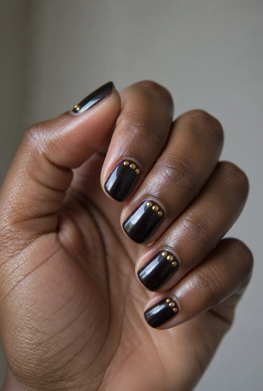 gold dot cluster nail art on deep brown skin