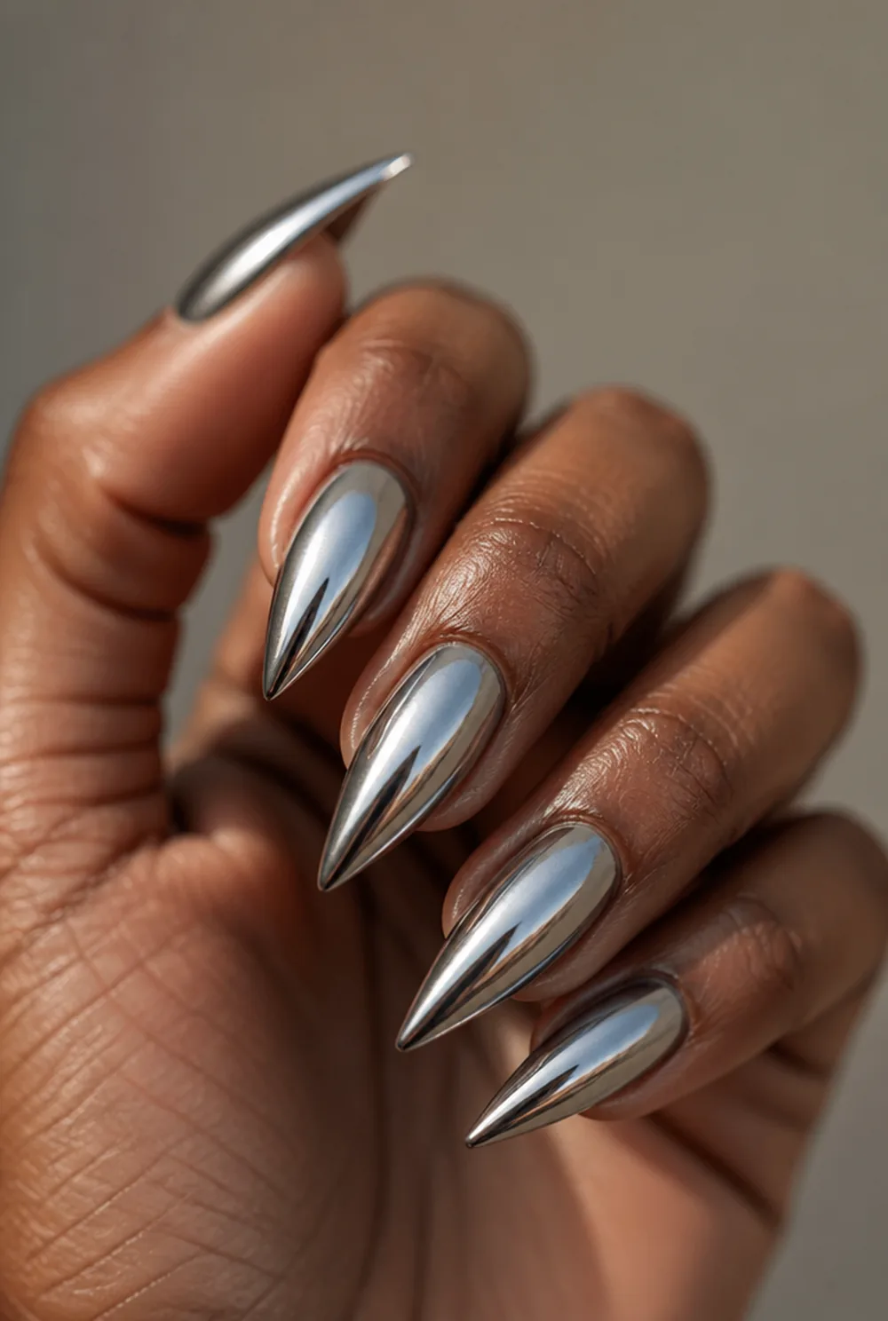 chrome stiletto nail art on deep brown skin