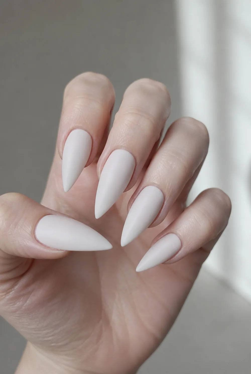 milky stiletto nail art on fair skin, short length