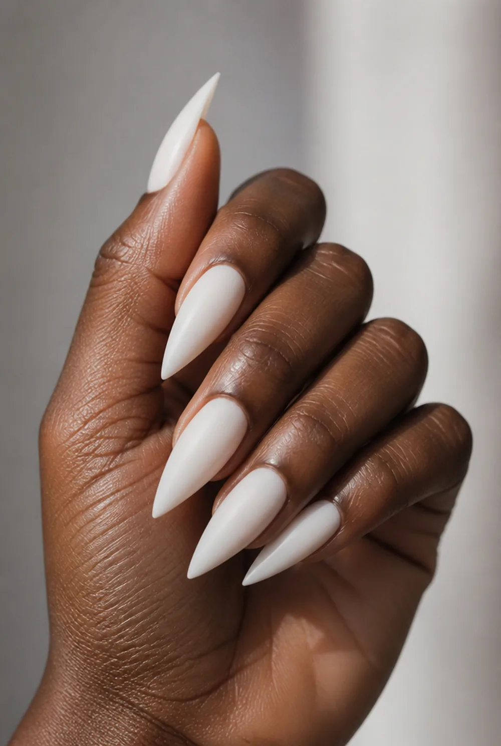 milky stiletto nail art on deep brown skin