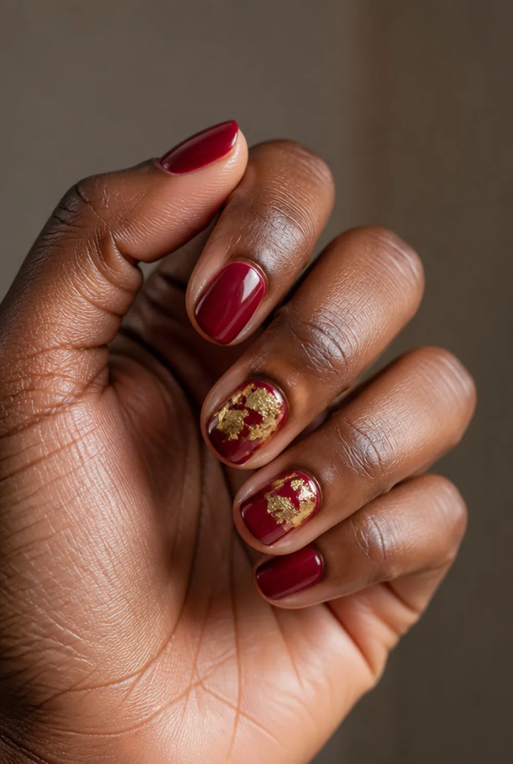red with gold foil nail art on deep brown skin