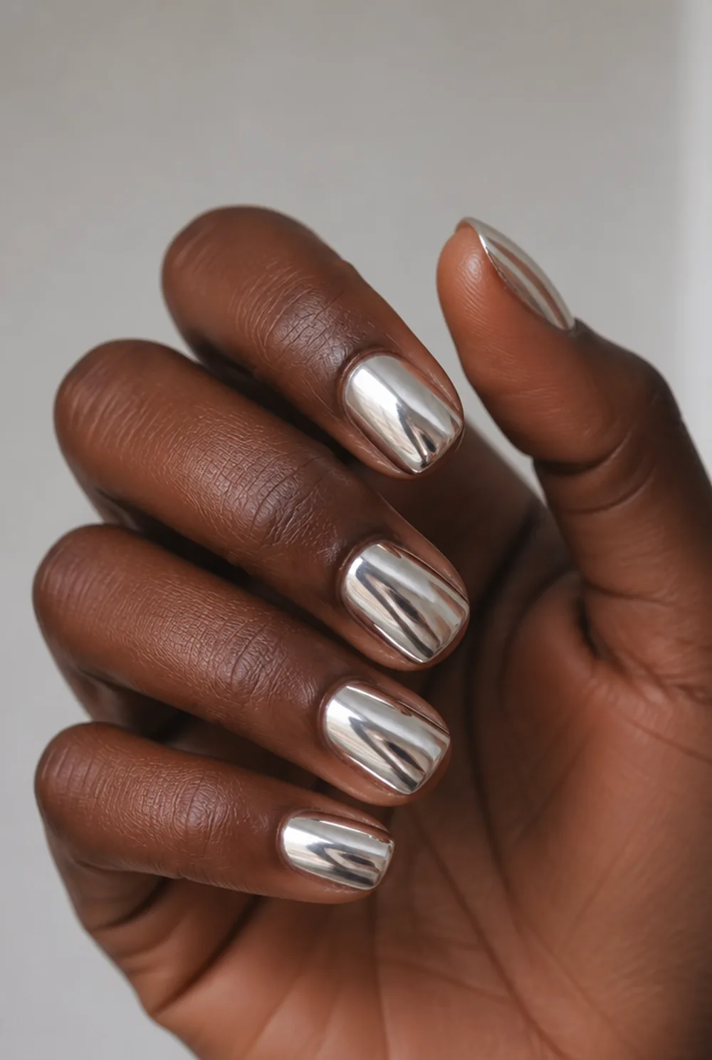 white chrome nail art on deep brown skin