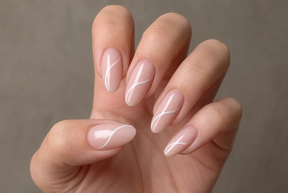 white swirl nail art on nude almond nails