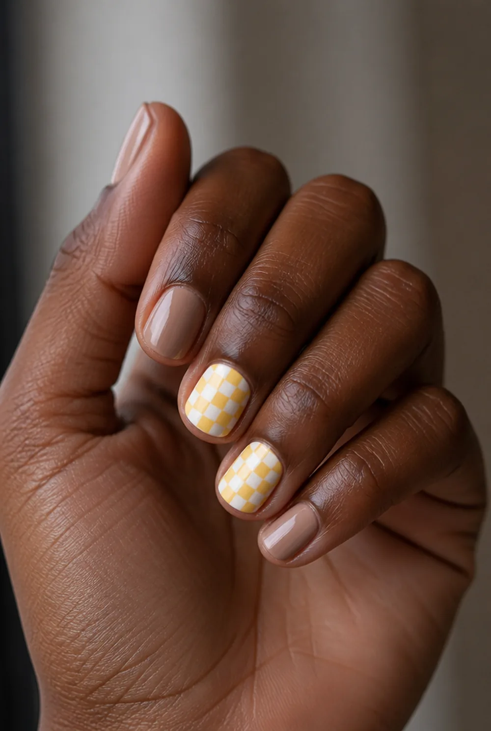 yellow checkerboard nail art on deep brown skin