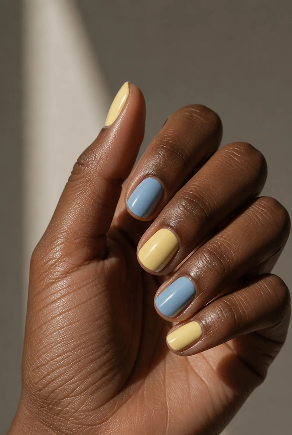 yellow and blue nail art on deep brown skin