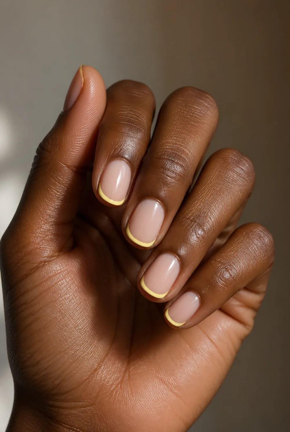 yellow french tip nail art on deep brown skin
