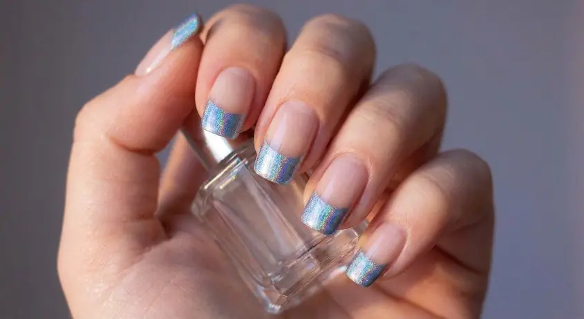 17wed - PolishedAndPrettyNails.com Holographic pale blue French tips on sheer nude nails, hand holding a small glass bottle