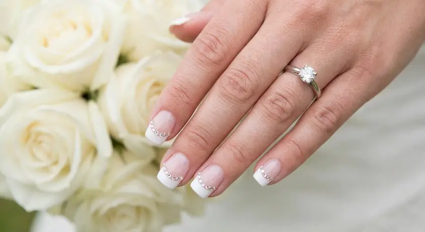6wed - PolishedAndPrettyNails.com Crystal French tips with sparkling white tips and a solitaire ring beside white roses