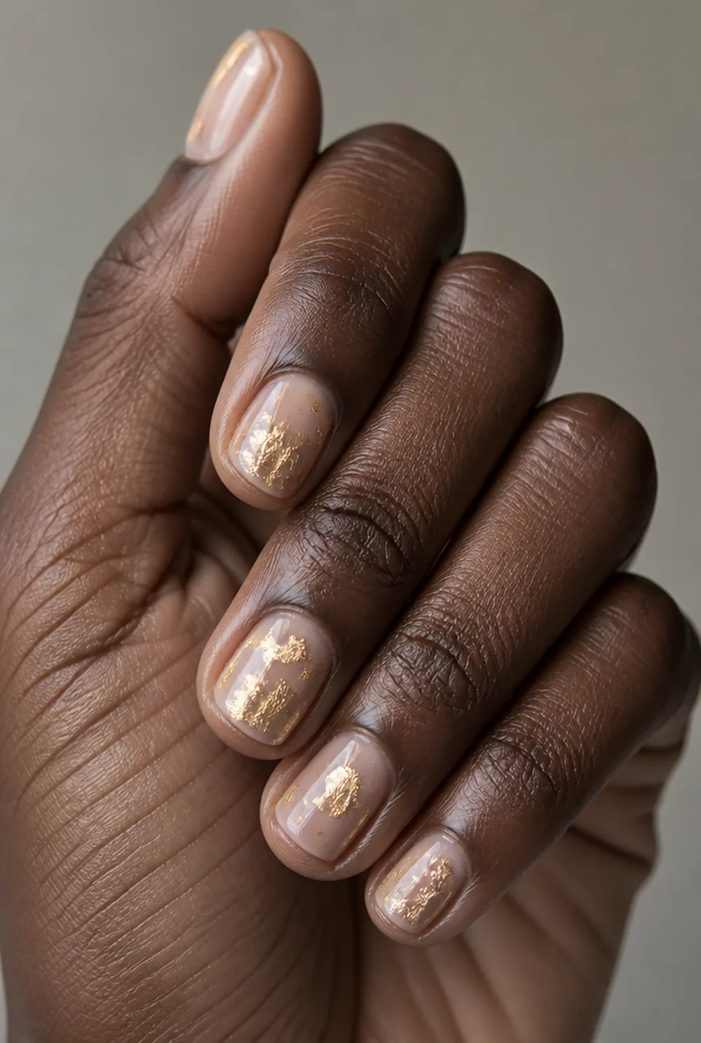 abstract gold leaf nail art on deep brown skin