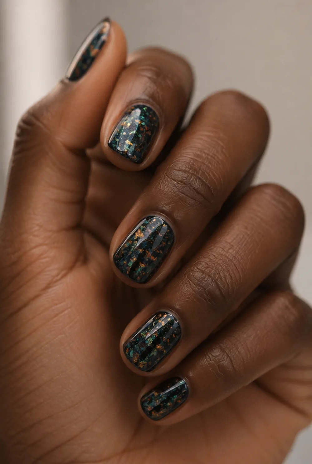 encapsulated chrome flakes nail art on deep brown skin