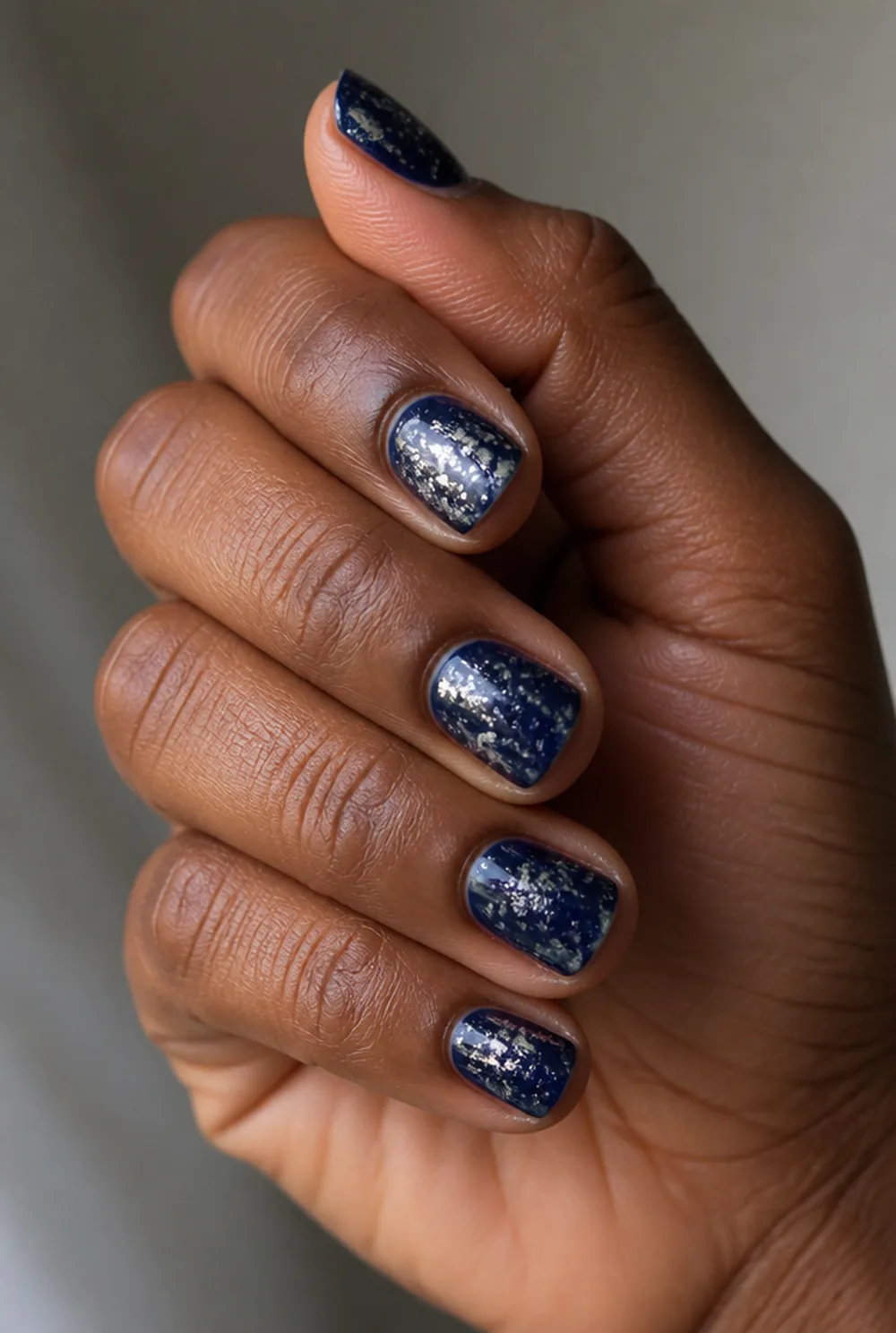 silver foil on navy nail art on deep brown skin