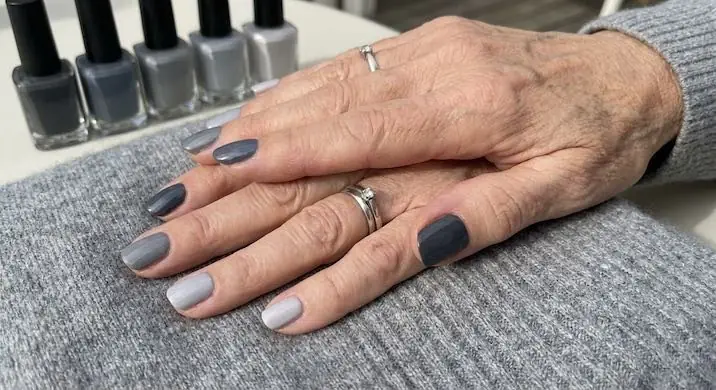 Monochromatic Gradient Elegance - PolishedAndPrettyNails.com Monochromatic gray gradient nails on mature hands beside gray polish bottles
