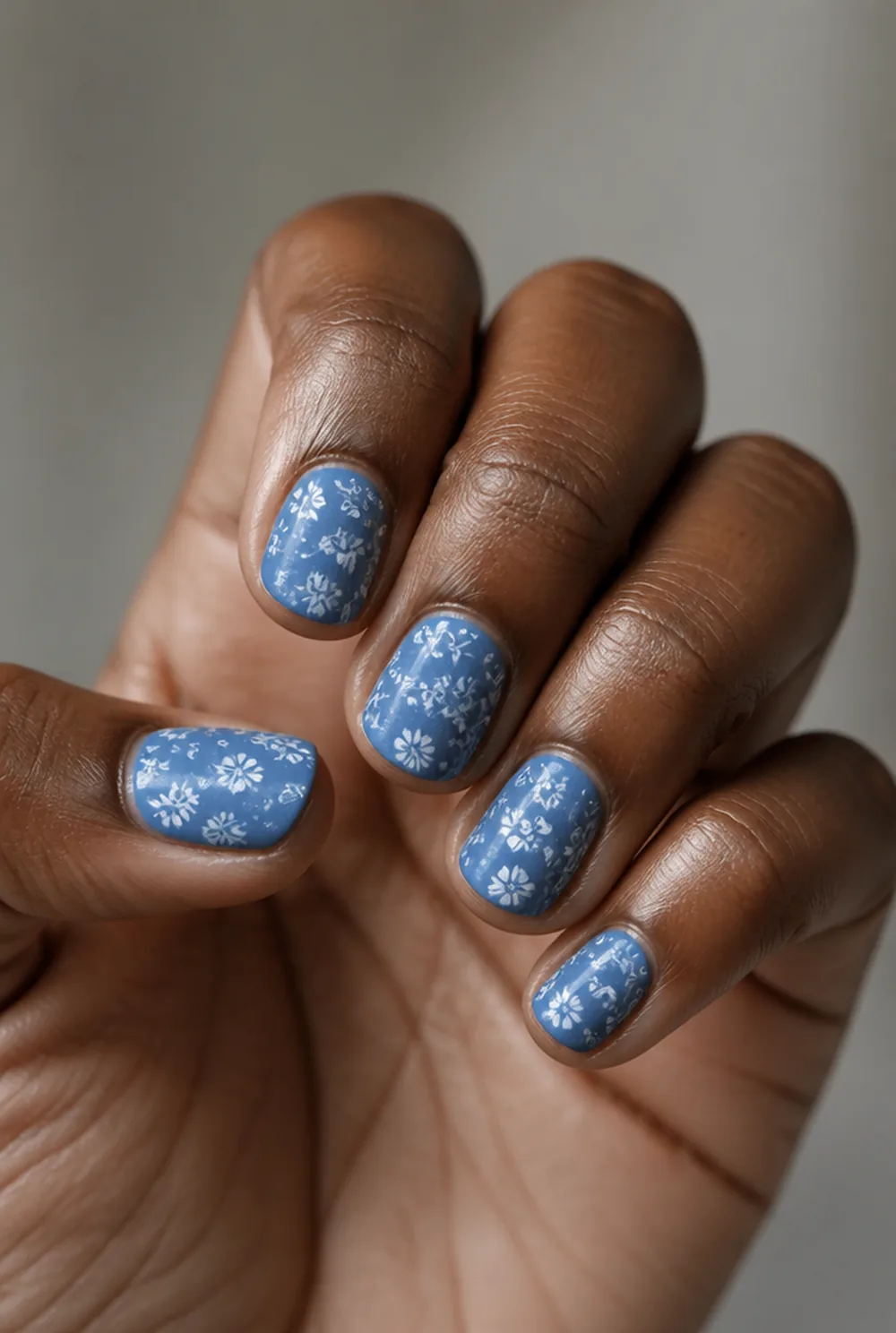 white florals on blue nail art on deep brown skin