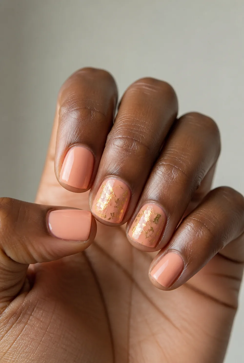 peach with gold foil nail art on deep brown skin