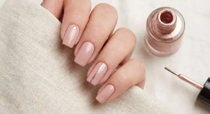Subtle Metallic Accents - PolishedAndPrettyNails.com Subtle rose gold metallic accent nails on sheer pink nails beside a polish bottle