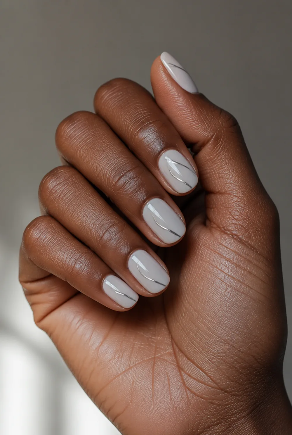 chrome swirl nail art on deep brown skin